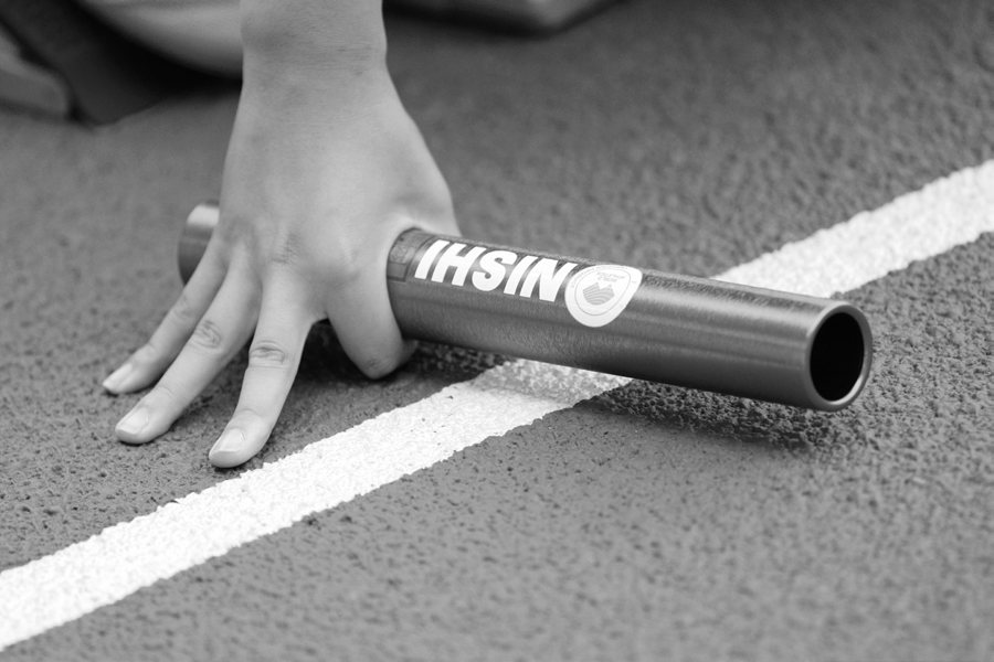 トラックのラインに置かれたNISHIのバトンと選手の手